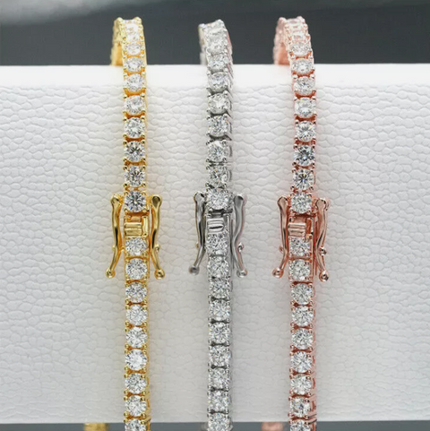 Three diamond bracelets in gold, silver, and rose gold on a white surface.